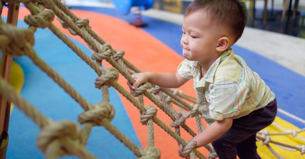 a toddler playing on a rope net