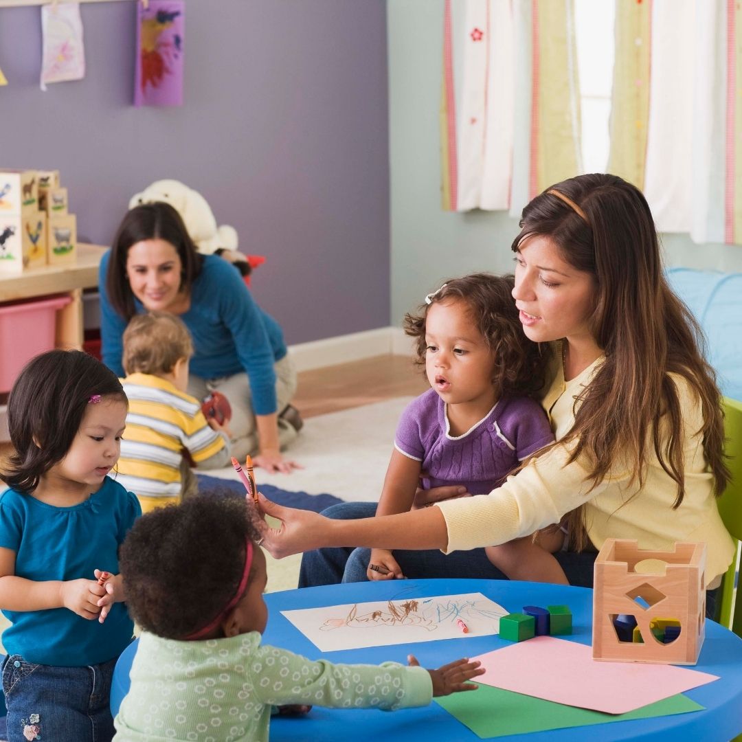 Teachers and children in a daycare classroom.